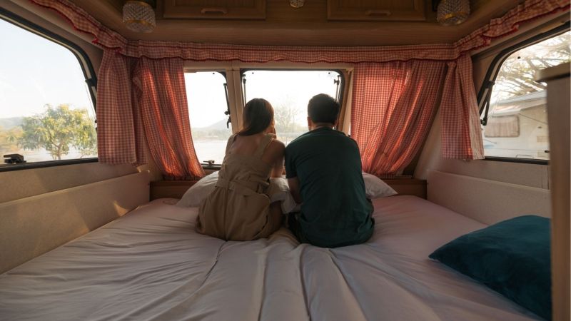 Couple sits on mattress in an RV