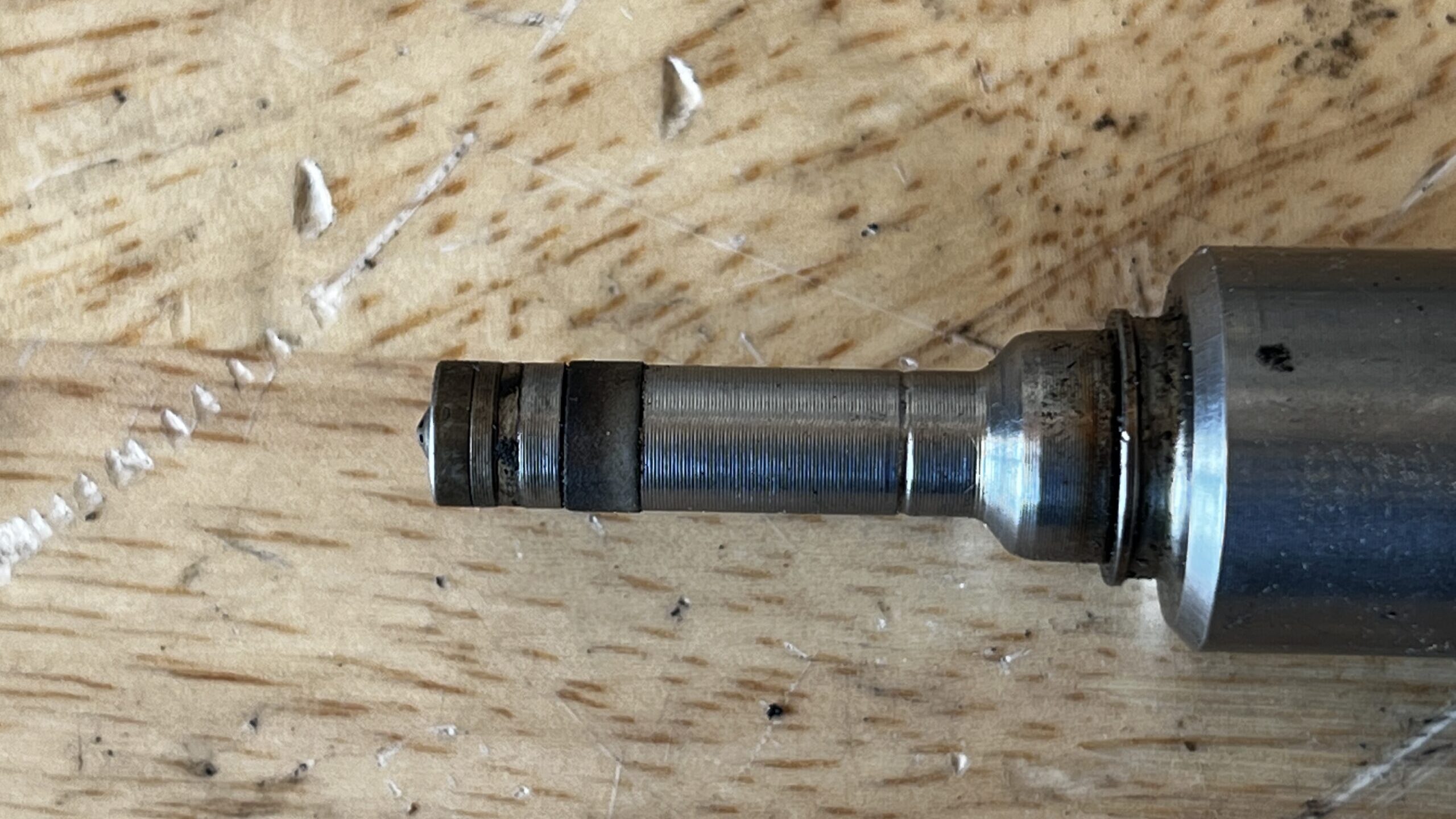 A closeup of the tip of a Volkswagen TSI fuel injector. The background is birch.