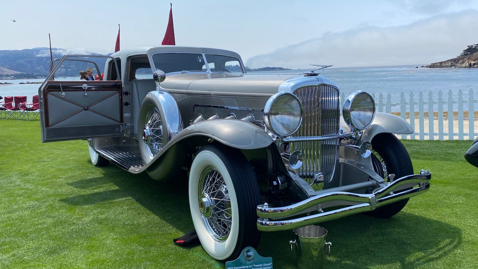 Classic car on green grass next to blue water in Pebble Beach