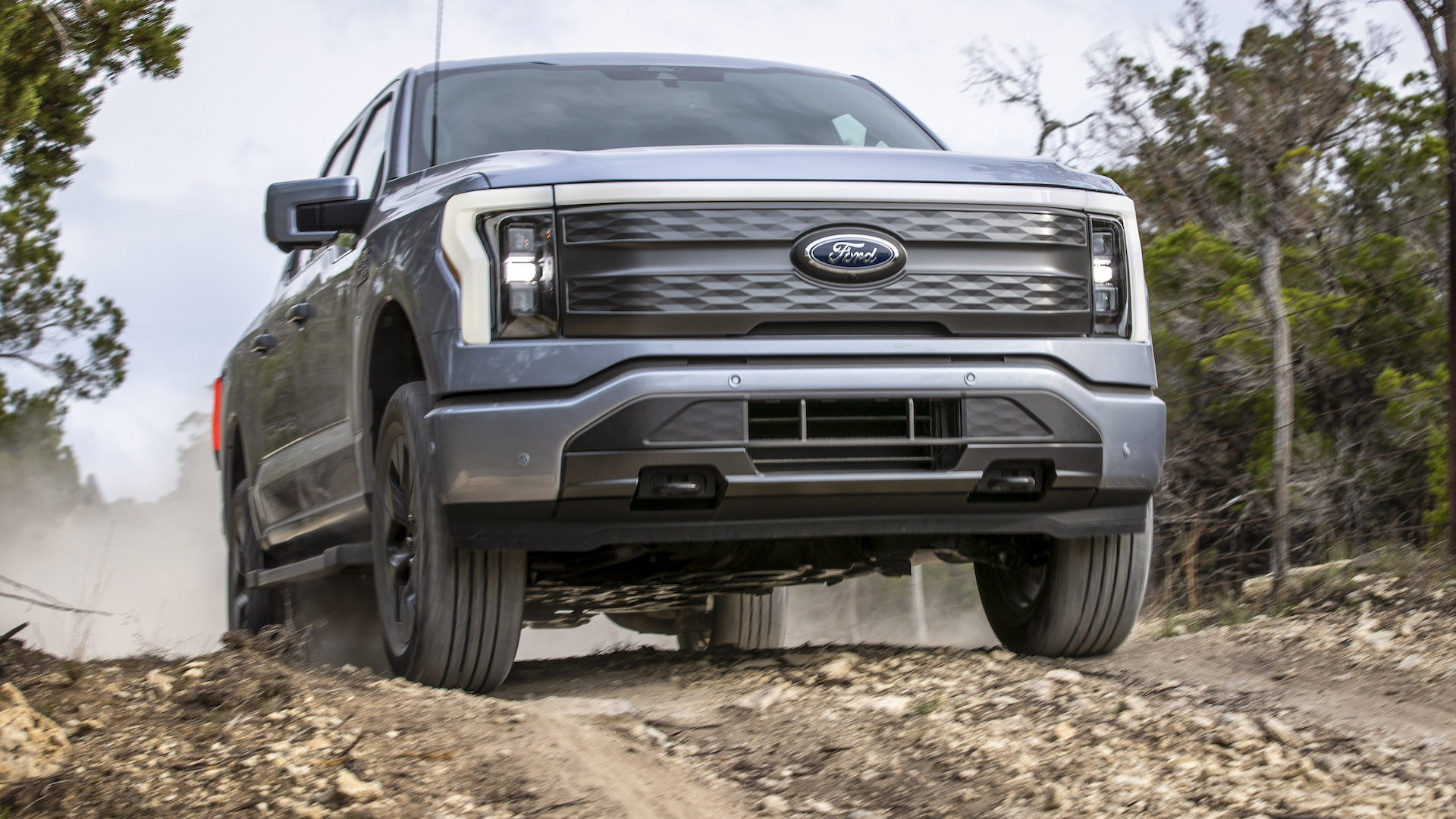 A Ford F-150 Lightning pickup truck cresting a hill, facing the camera