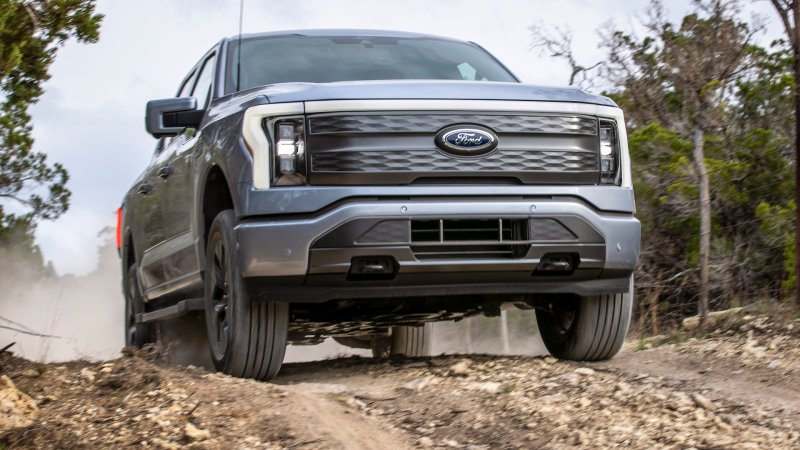 A Ford F-150 Lightning pickup truck cresting a hill, facing the camera