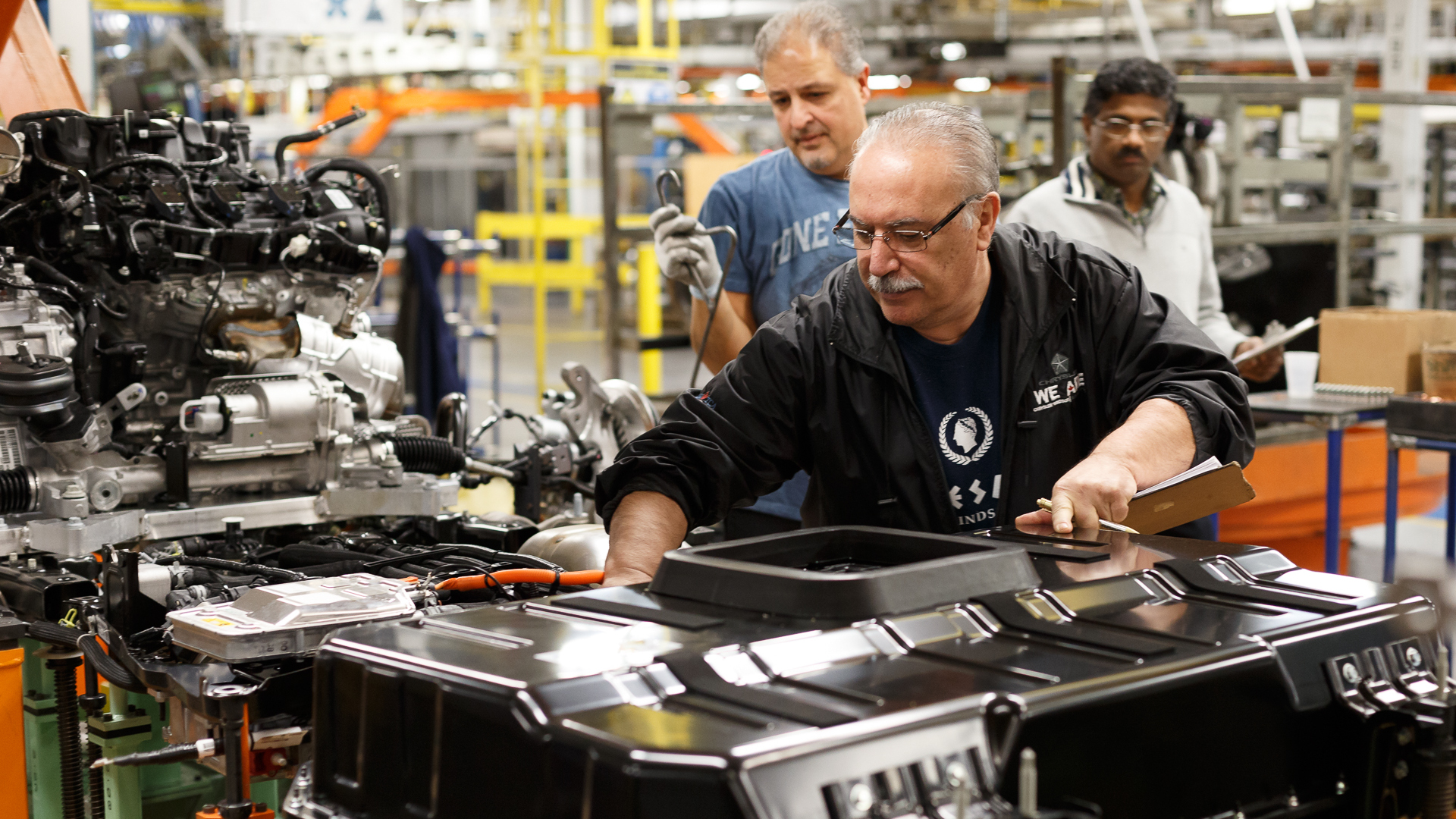 man assembles battery into car in Stellantis plant