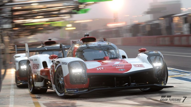 A Toyota GR010 Hybrid race car pulls out of the pits at Le Mans in Gran Turismo 7.