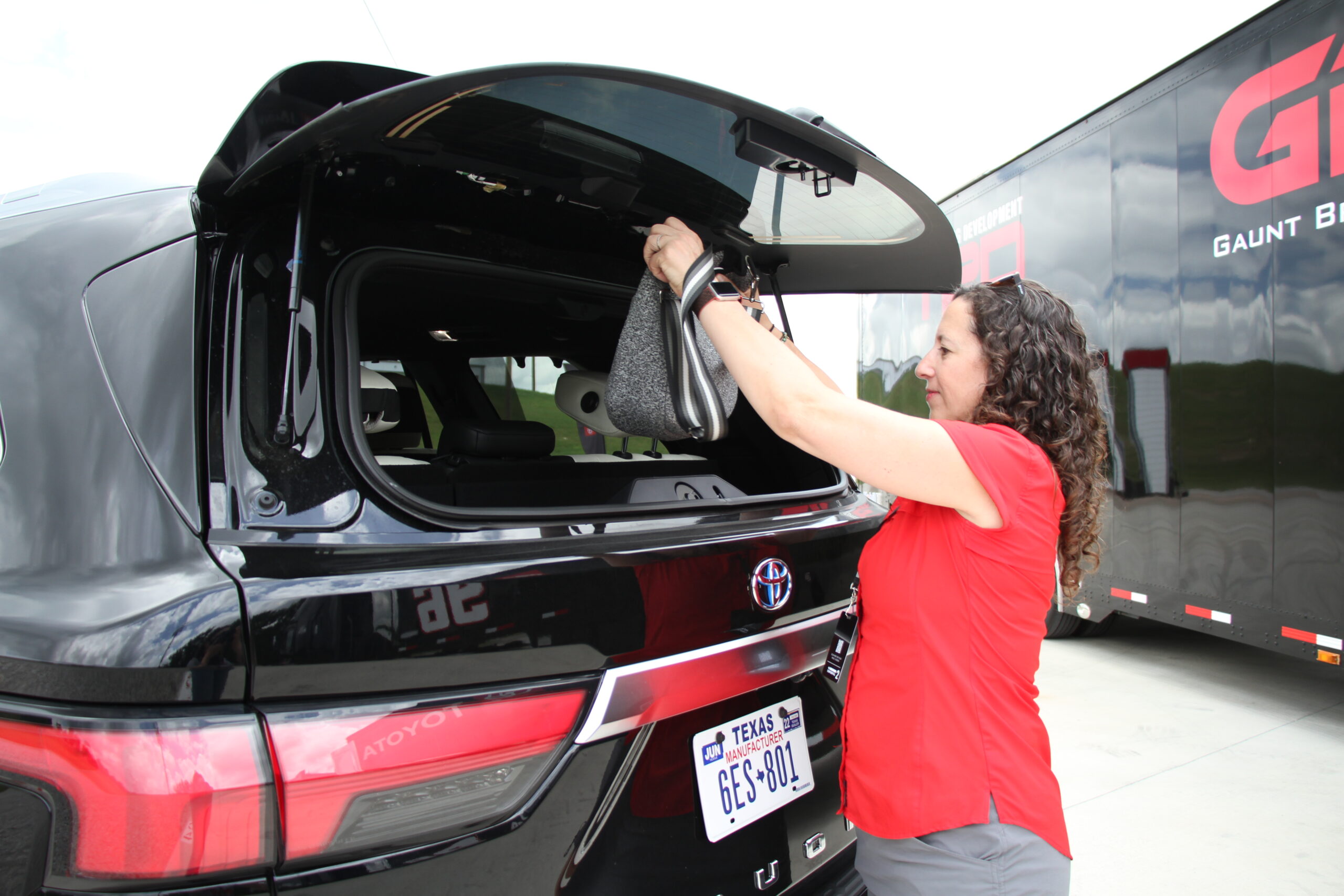 Opening the rear glass of a Toyota Sequoia to store a purse.