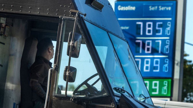 UPS truck at a gas station in front of price board