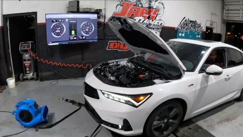 A white 2023 Acura Integra is strapped to a dyno with its hood open.