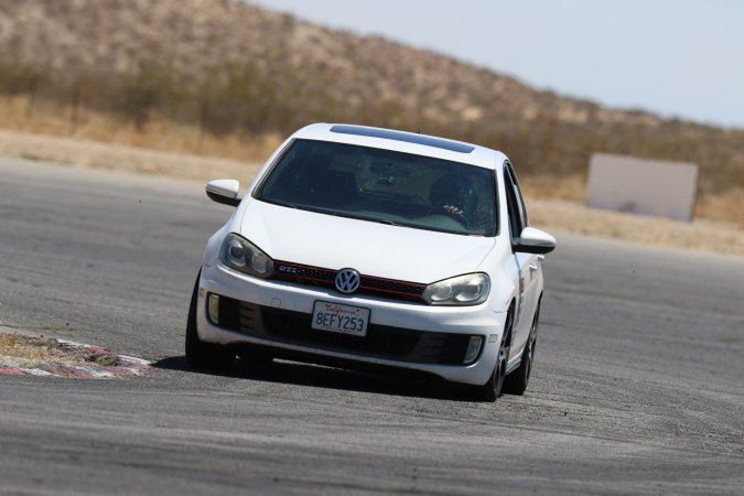 A white 2010 Volkswagen GTI entering the final turn at Streets of Willow handling course. It is mobbing.