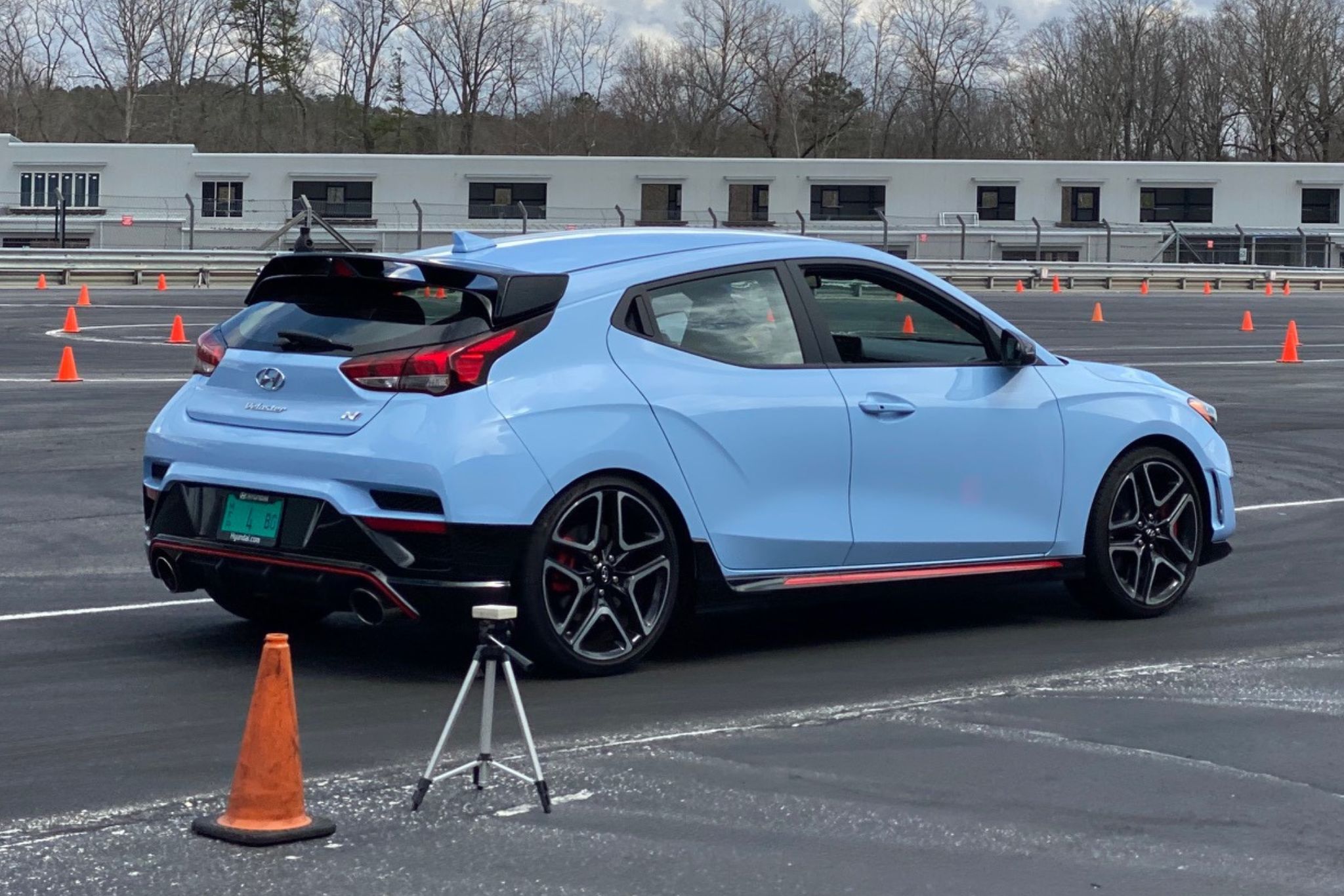 blue hatchback in front of orange cone on autocross track