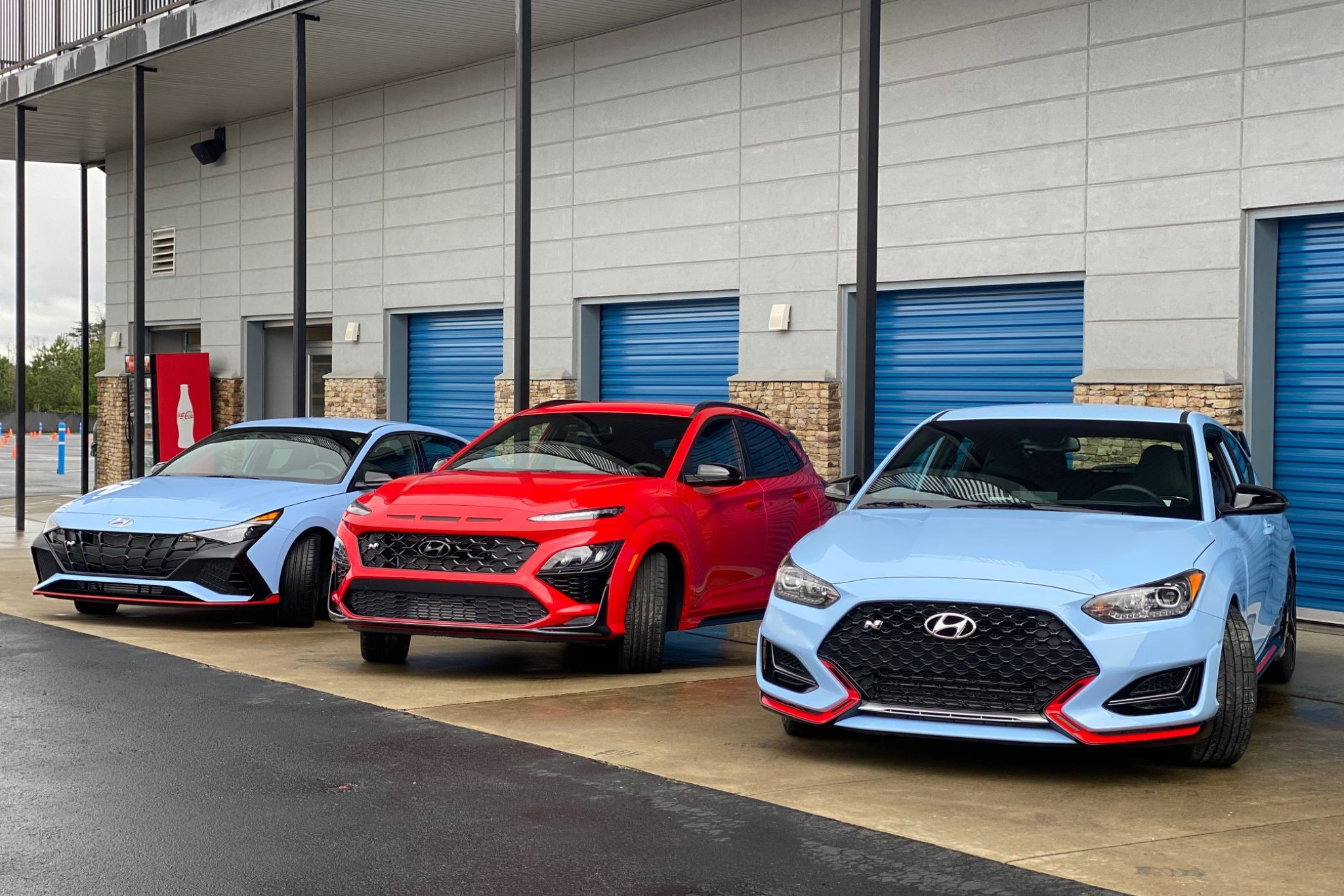 blue car, red car, and blue car lined up in front of garage