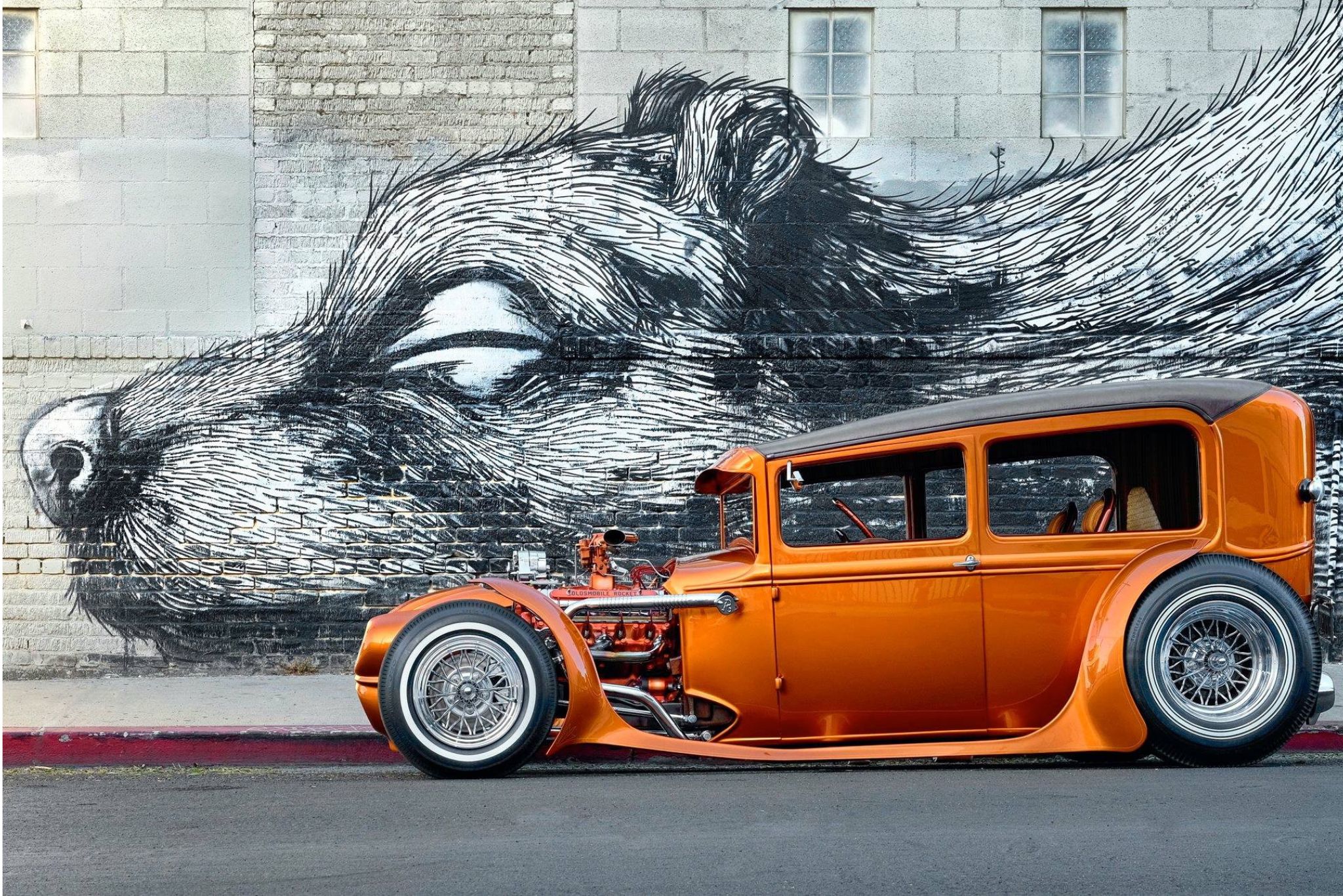 Orange hot rod in front of bear mural