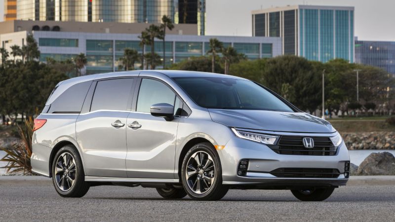 silver minivan in front of city skyline