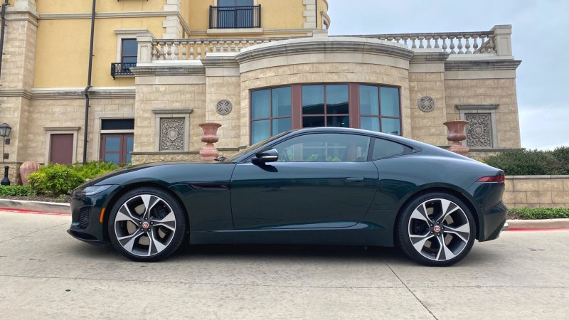 green Jaguar in front of tan building