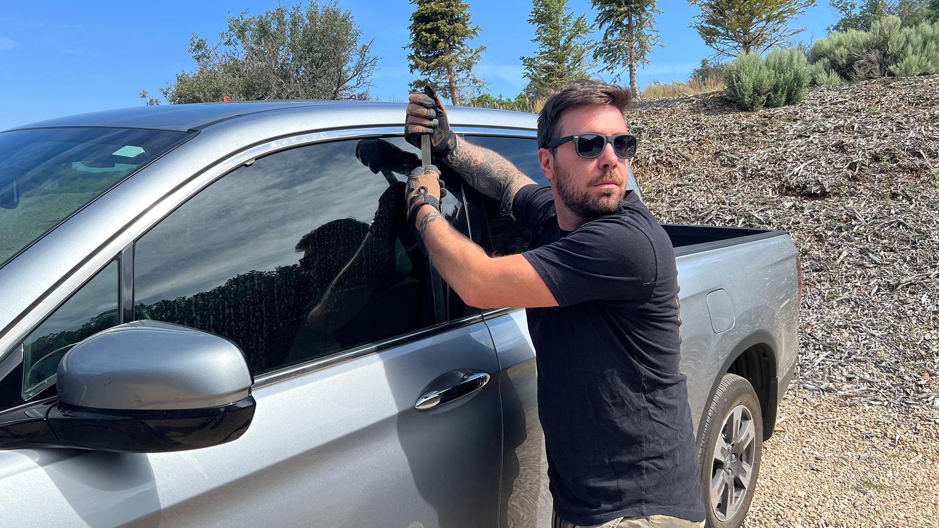 A person trying to steal a car with a door lock tool.