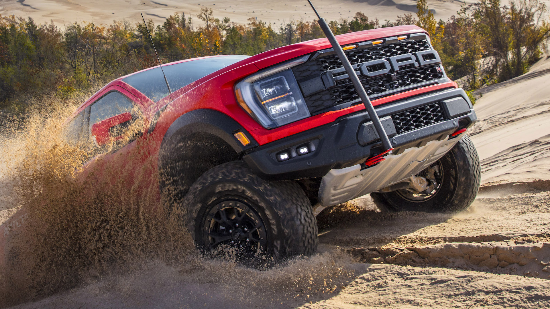 2023 Ford F-150 Raptor R scatters sand as it crests a hill