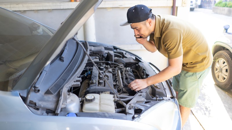 Mechanic fixing car at home.