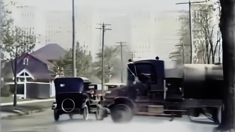 A car narrowly avoid being hit by a truck in 1920s Detroit, Michgan