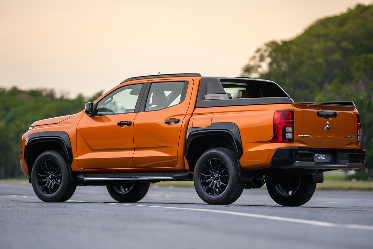 2024 Mitsubishi Triton rear three-quarter in orange against a forested background