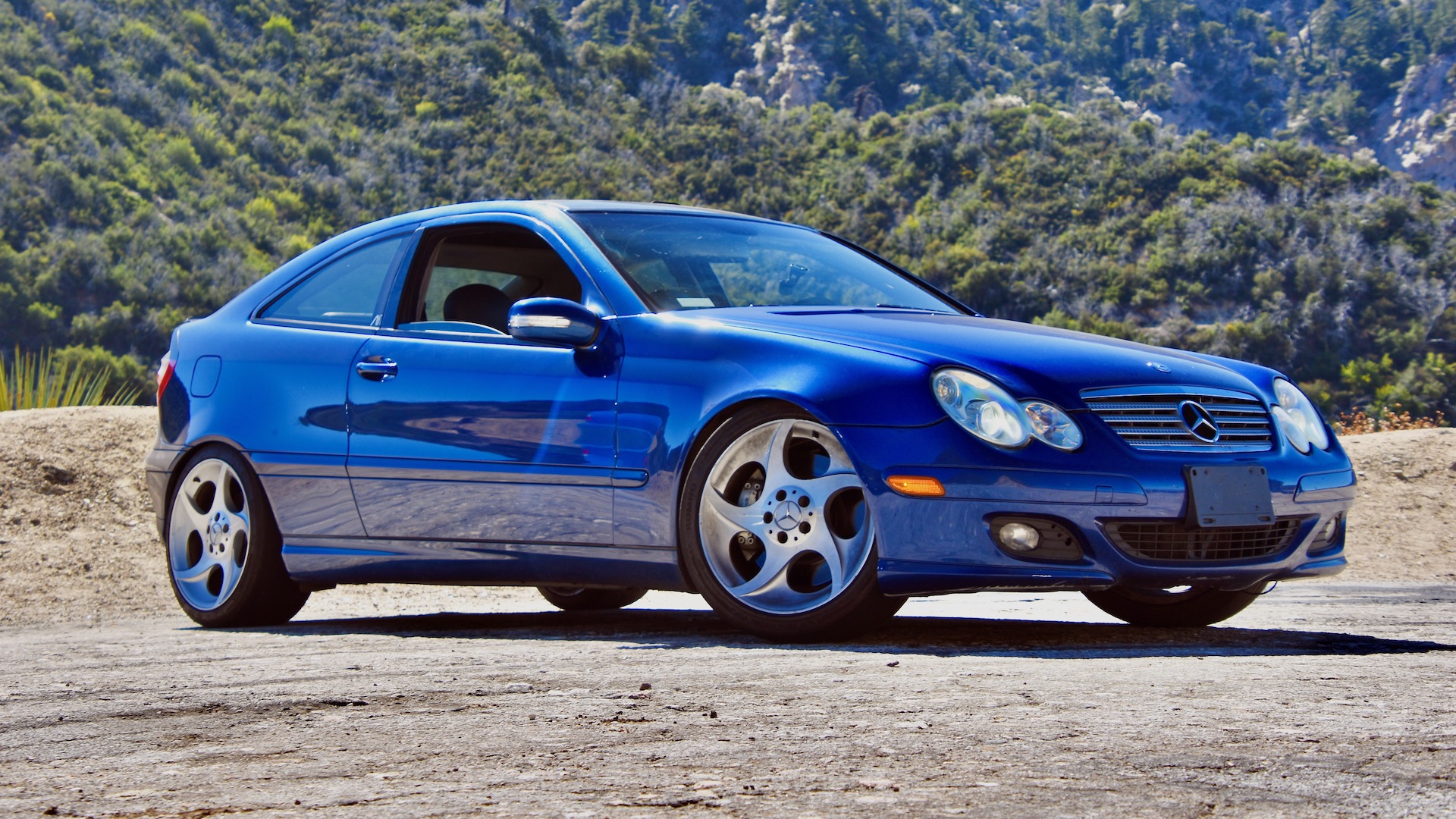 Blue Mercedes C320 Sportcoupe against a forested background