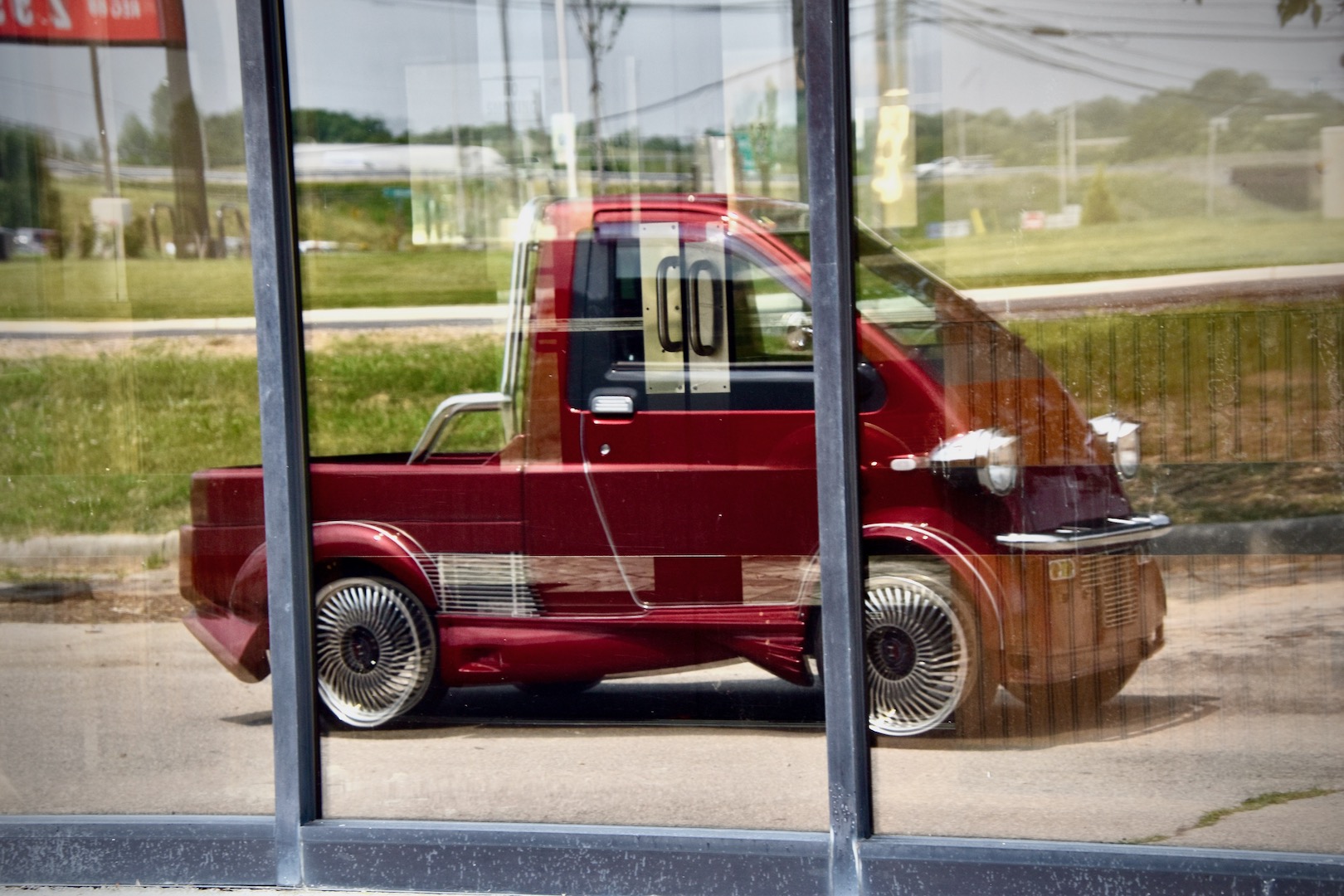 1996 Daihatsu Midget II reflected in the window of a defunct Pizza Hut