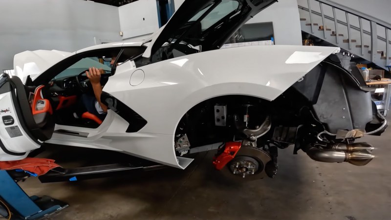 A white Chevy Corvette C8 with its engine cover and rear bumper removed as its 8.1-liter Big Block engine is started for a test.