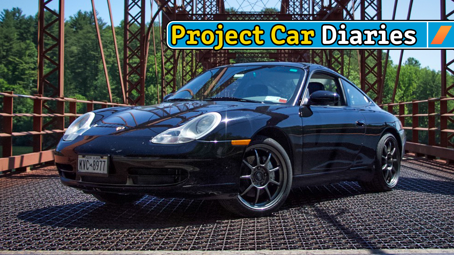 Black Porsche 911 gleaming on a bridge.