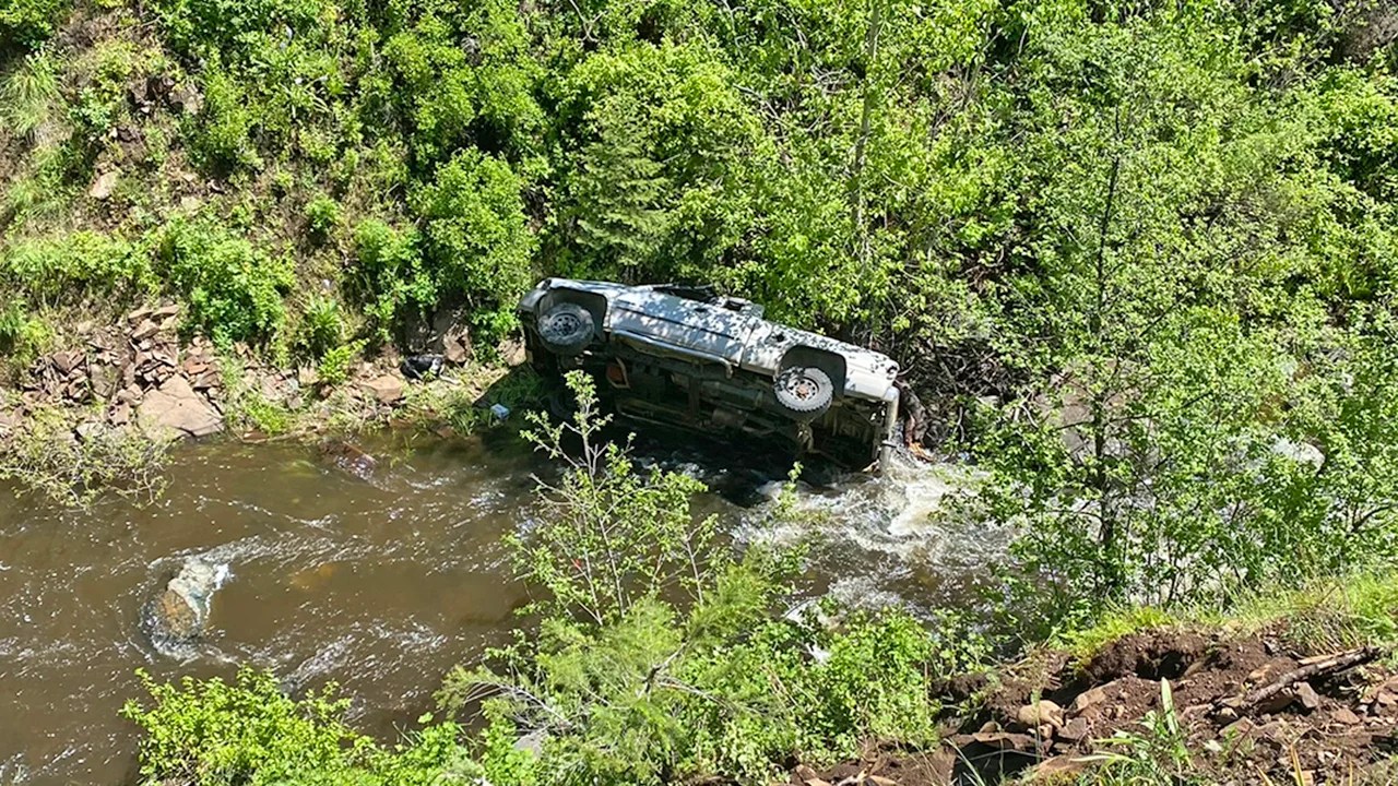 Vehicle on its side lodged in a creek.