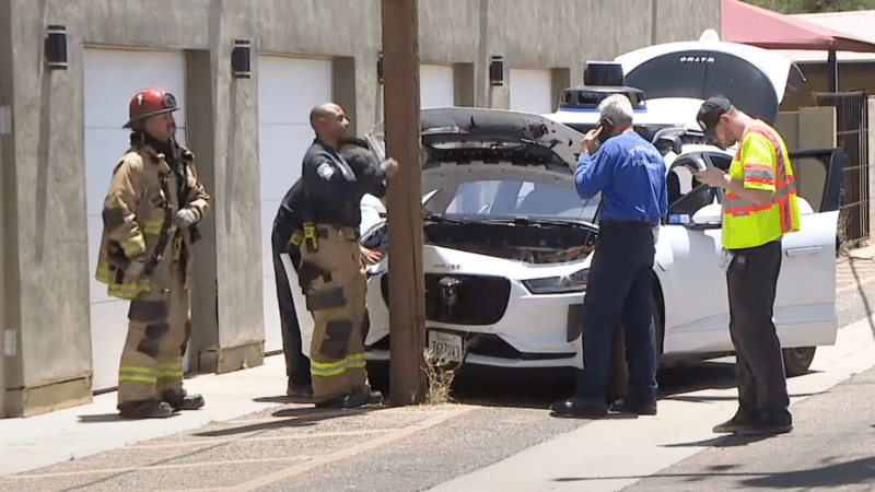 Authorities stand by a Waymo vehicle that has crashed into a telephone pole.