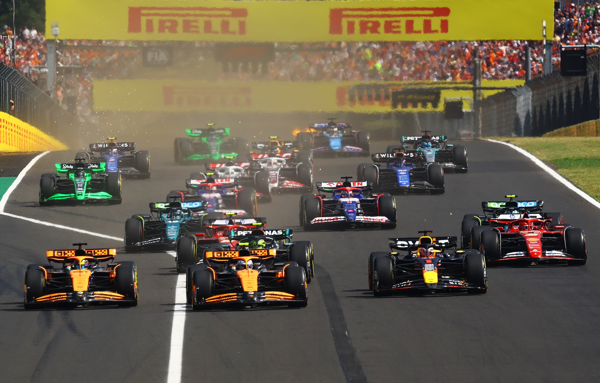 BUDAPEST, HUNGARY - JULY 21: Oscar Piastri of Australia driving the (81) McLaren MCL38 Mercedes, Lando Norris of Great Britain driving the (4) McLaren MCL38 Mercedes and Max Verstappen of the Netherlands driving the (1) Oracle Red Bull Racing RB20 lead the field into turn one at the start during the F1 Grand Prix of Hungary at Hungaroring on July 21, 2024 in Budapest, Hungary. (Photo by Mark Thompson/Getty Images)