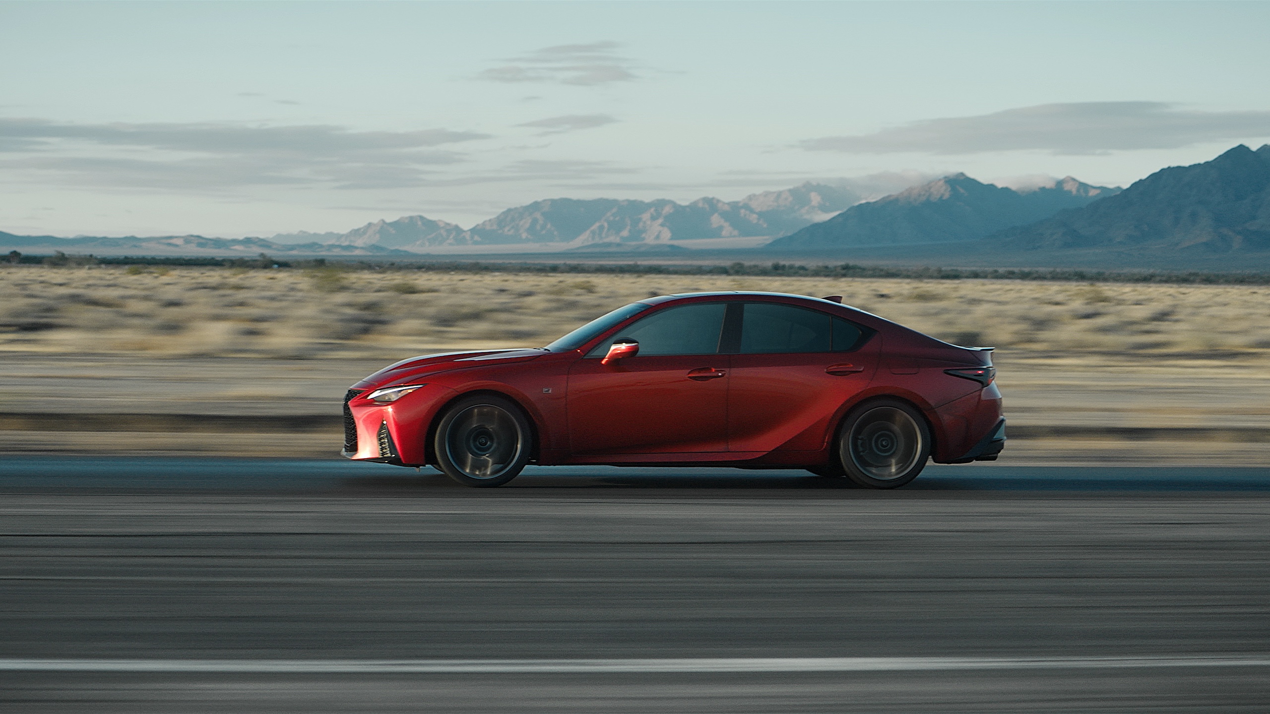 Lexus IS 500 driving on road from side view.