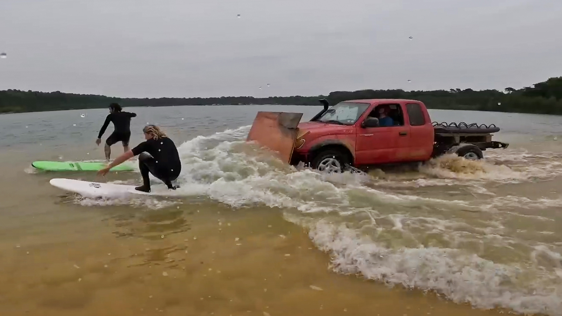 Surfers using a truck with a plow as a wave generator