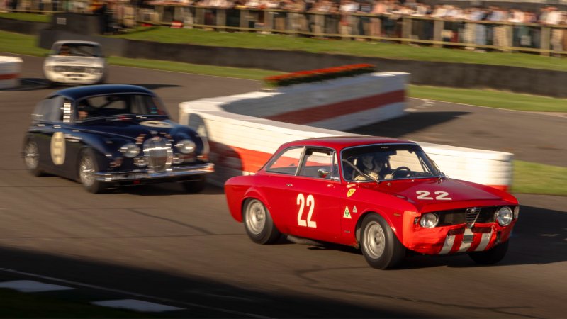 A Jaguar racing an Alfa Romeo through the chicane at the 2024 Goodwood Revival.