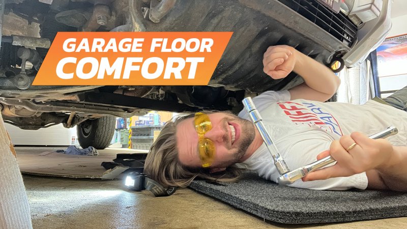 Mechanic working under a car with a Husky Liners Garage Mat.