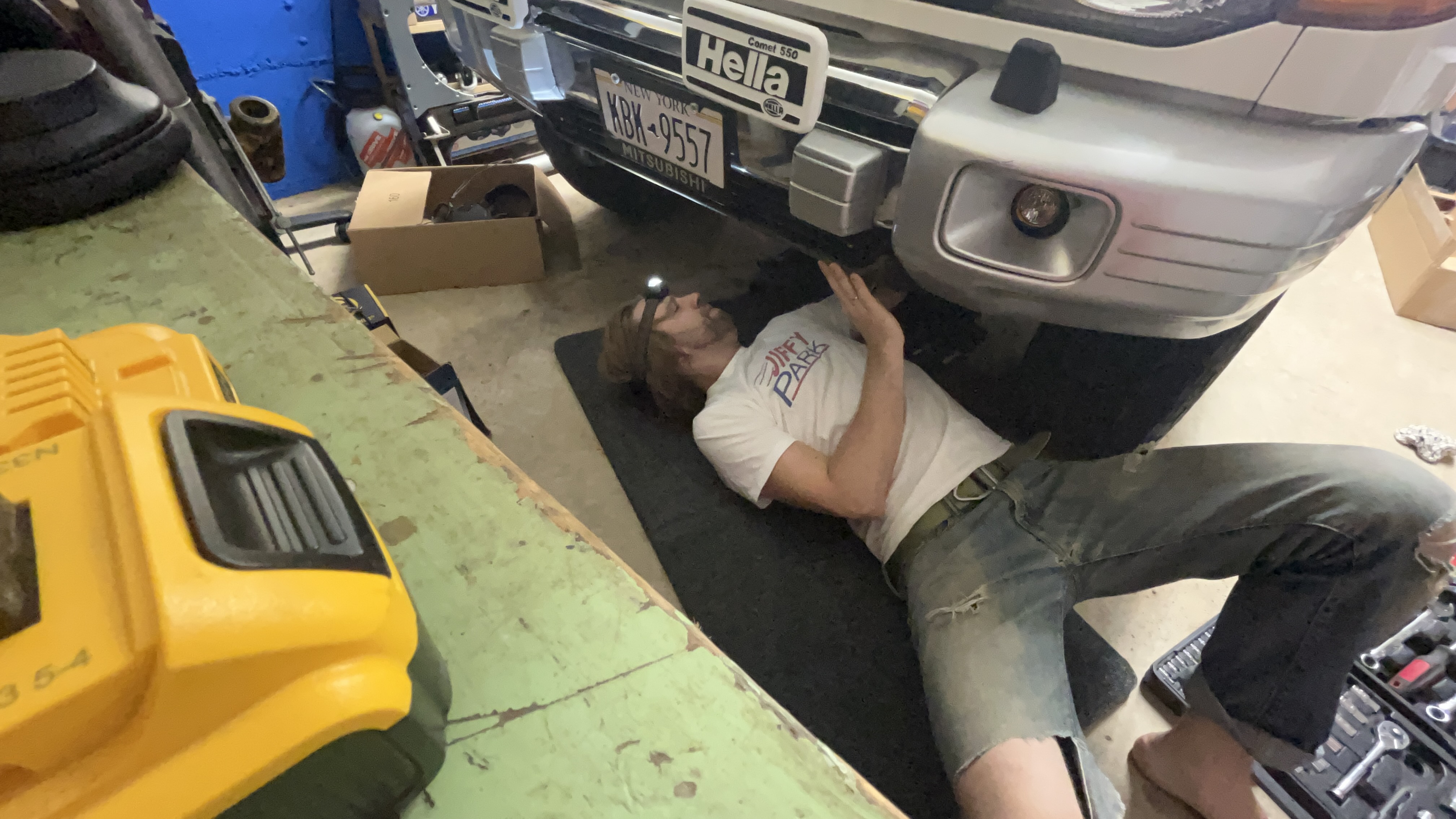 Mechanic working on car using Husky Liners Garage Mat.