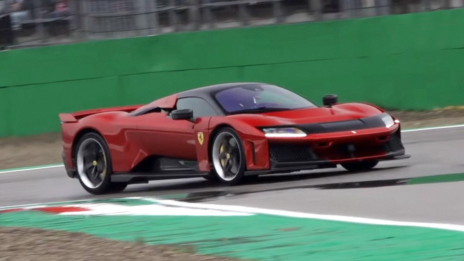 A red Ferrari F80 rounding a corner at the Imola circuit during a Ferrari demonstration.