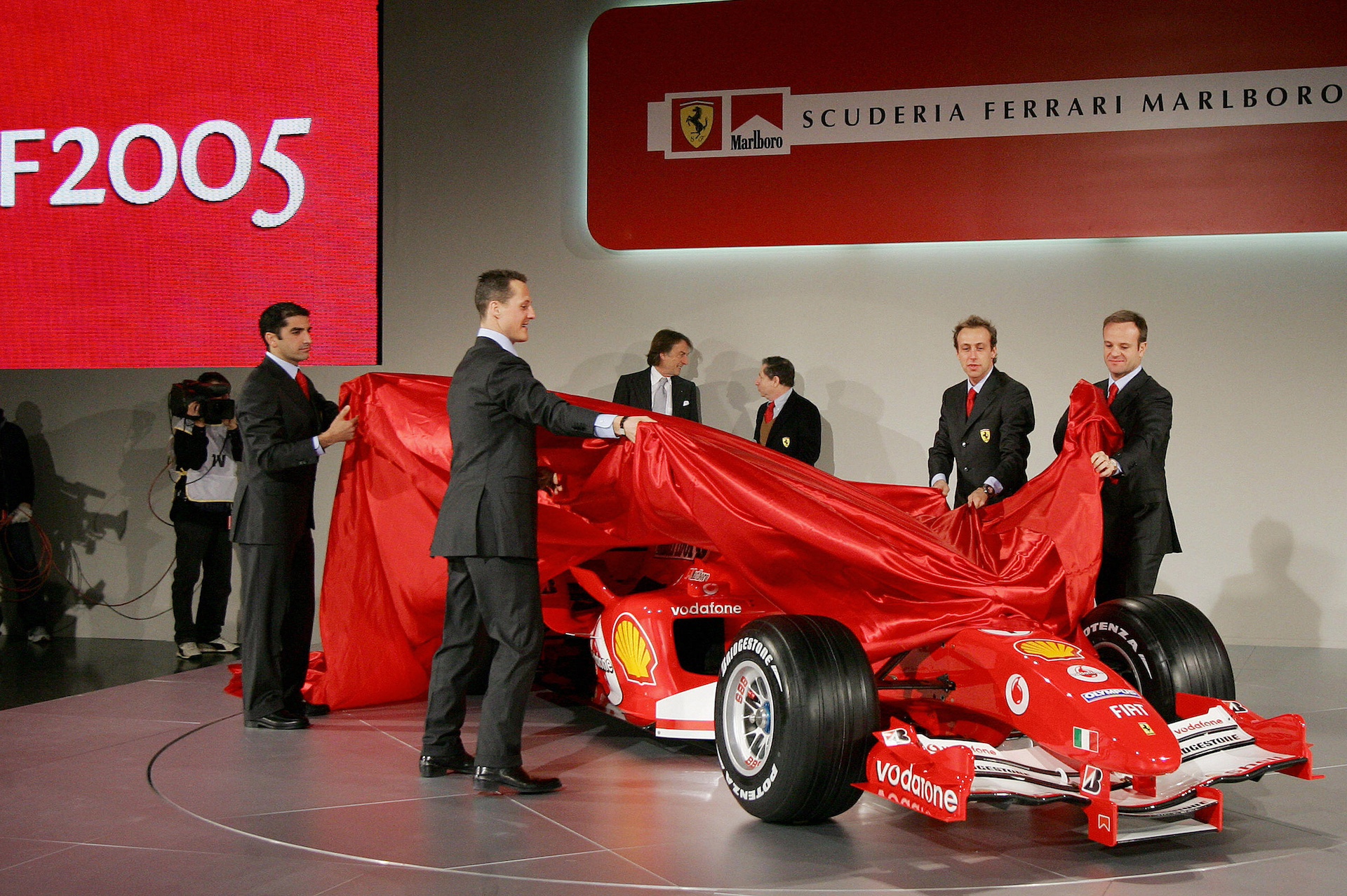 MARANELLO, ITALY: German Ferrari's drivers Michael Schumacher (C), Brazilian Rubens Barrichello (R), test driver Italian Luca Badoer (2nd R) and Marc Gene (L) of Spain unveil the new Ferrari F1 Car F2005 during official presentation in the Ferrari headquarter in Maranello 25 February 2005. AFP PHOTO/ Paco SERINELLI (Photo credit should read PACO SERINELLI/AFP via Getty Images)