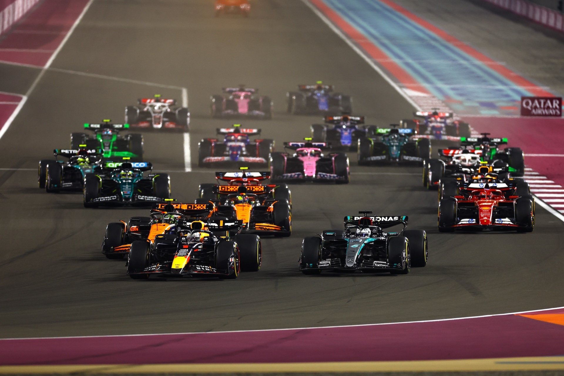 LUSAIL CITY, QATAR - DECEMBER 01: Max Verstappen of the Netherlands driving the (1) Oracle Red Bull Racing RB20 and George Russell of Great Britain driving the (63) Mercedes AMG Petronas F1 Team W15 lead the field into turn 1 at the start during the F1 Grand Prix of Qatar at Lusail International Circuit on December 01, 2024 in Lusail City, Qatar. (Photo by Mark Thompson/Getty Images)