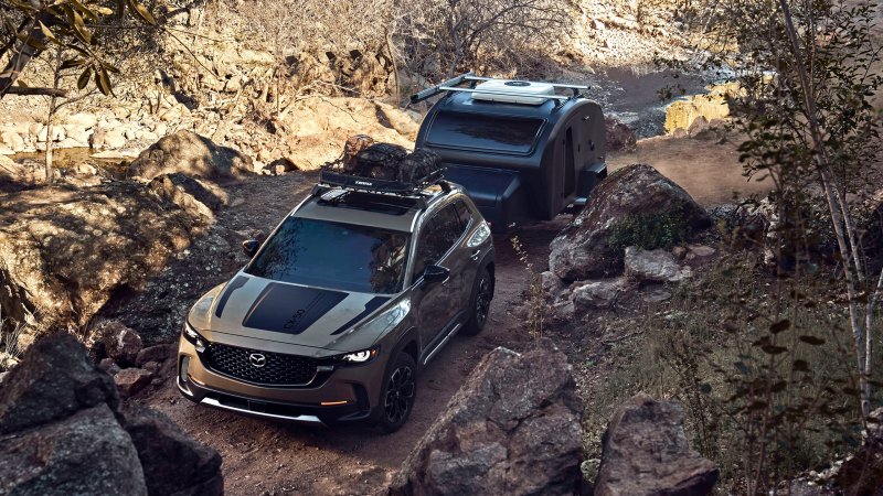 Mazda CX-50 towing a trailer on a dirt trail.