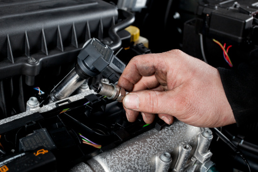 A mechanic working on a vehicle’s spark plugs.