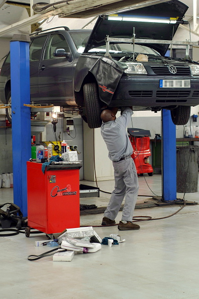 A man repairing a VW on a lift at a car dealership