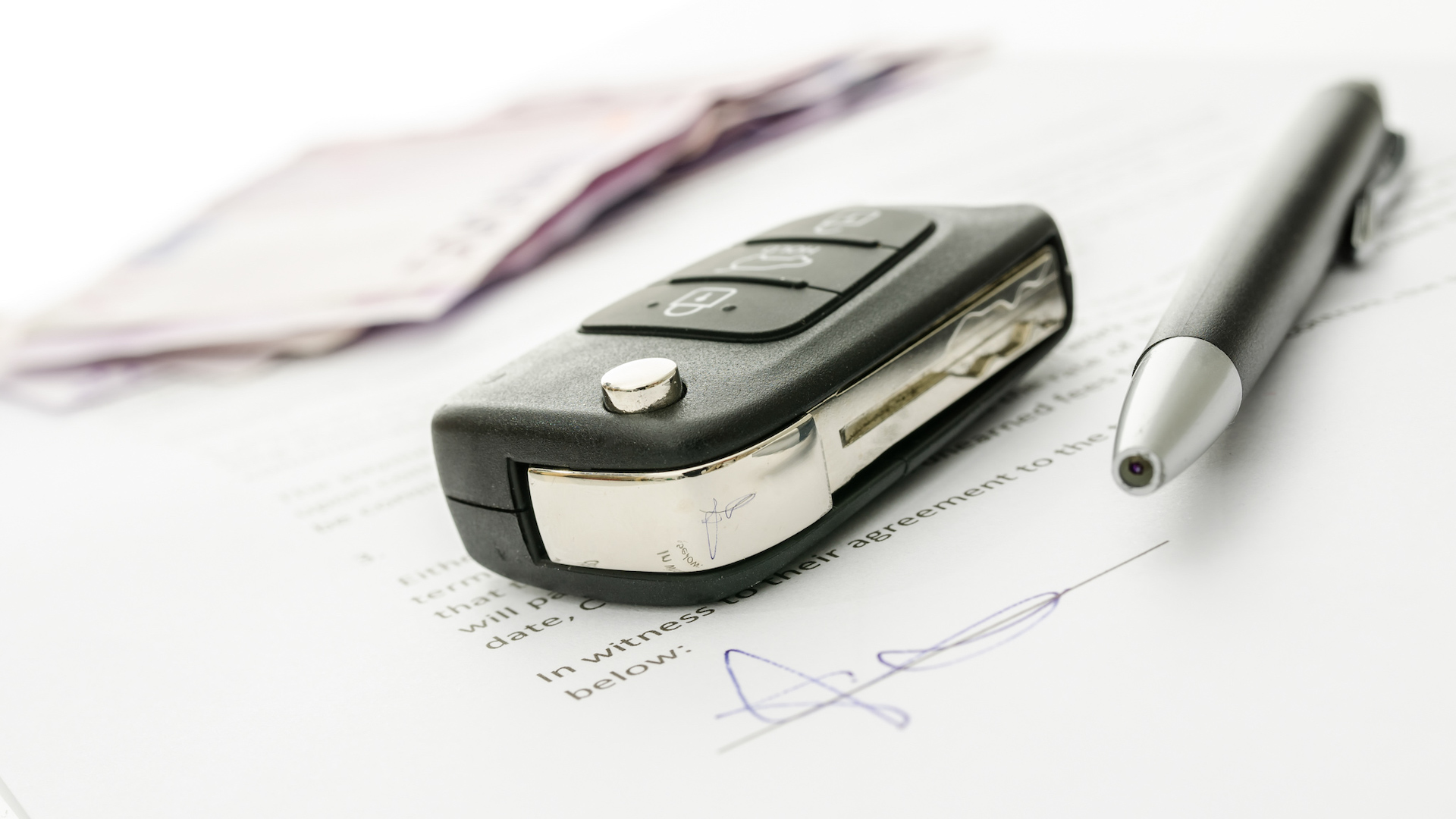 A key and pen sit on top of signed paperwork. 