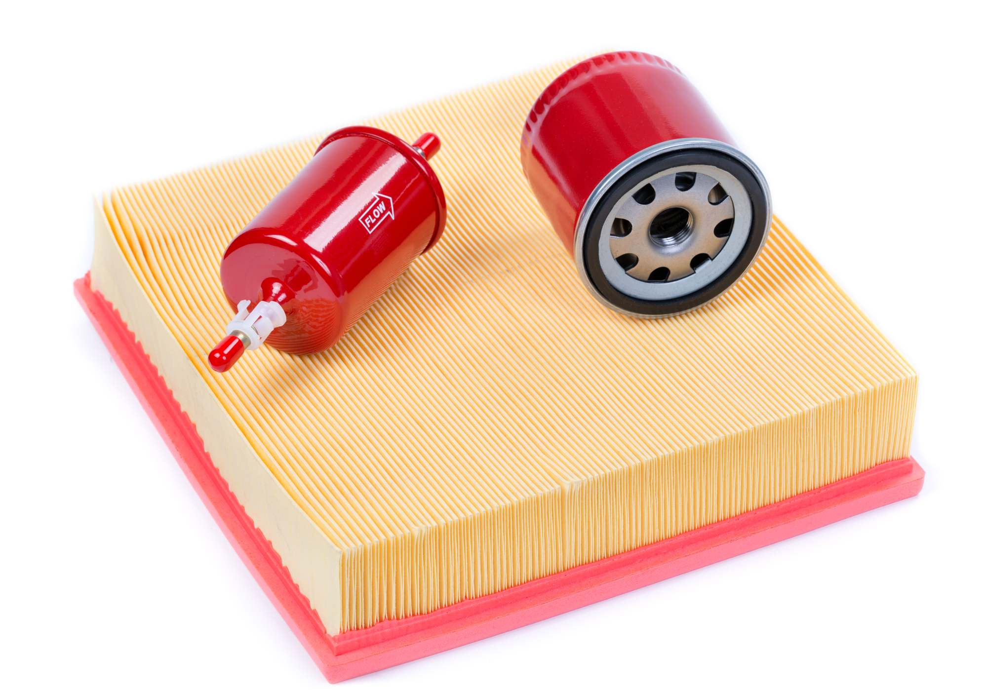 A red fuel filter and red oil filter sit on top of an off-white air filter.