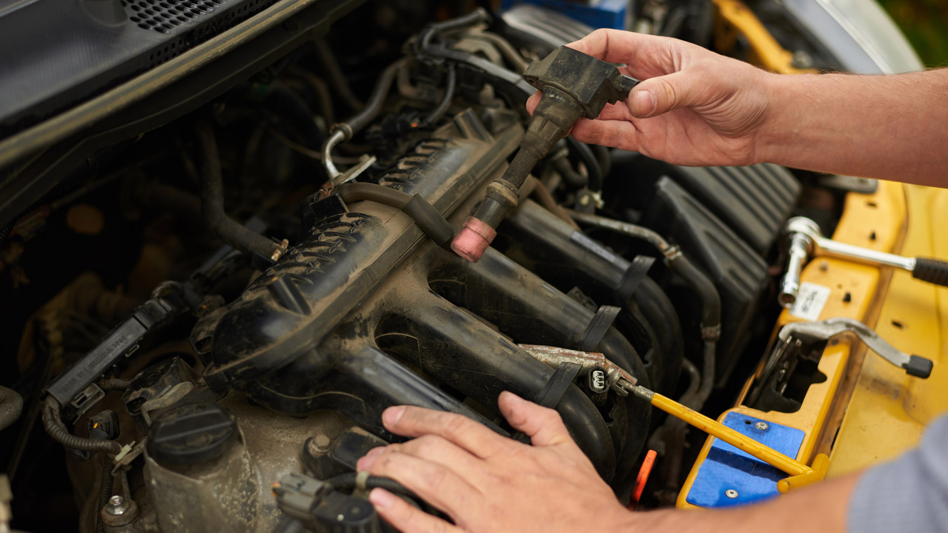 A man checks his ignition coils and spark plugs.