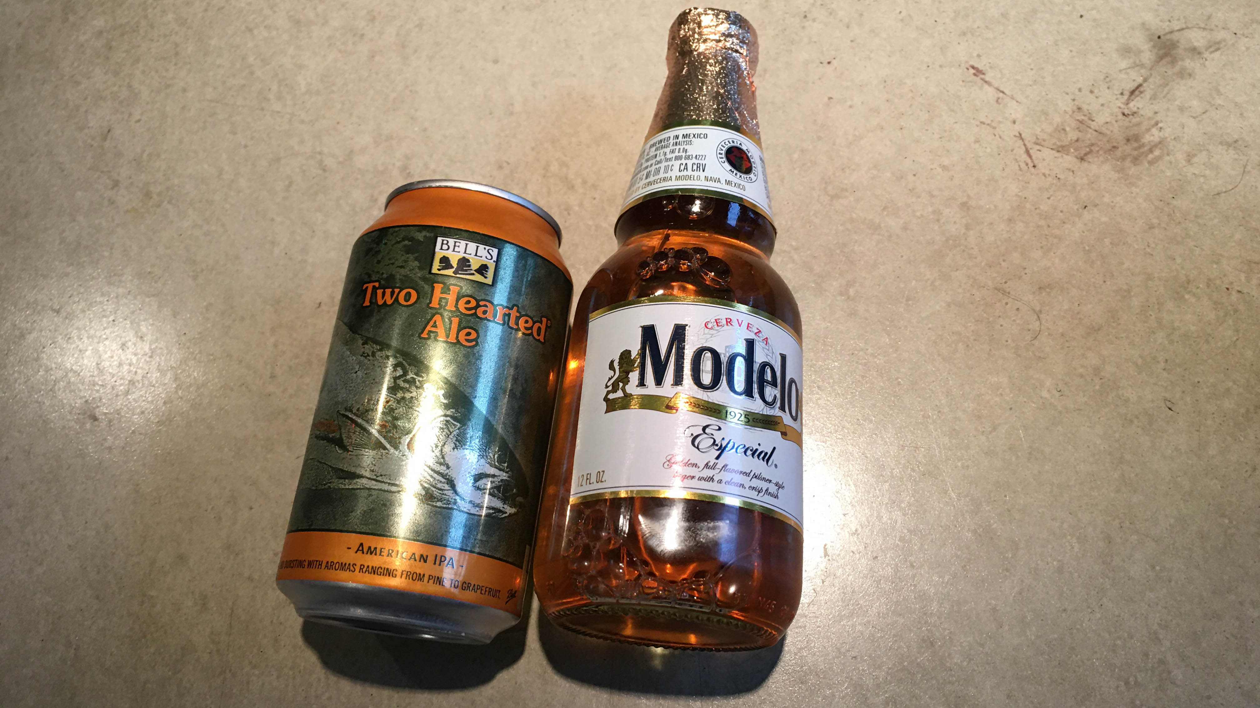 A Bell's Two Hearted Ale and a Modelo on concrete.