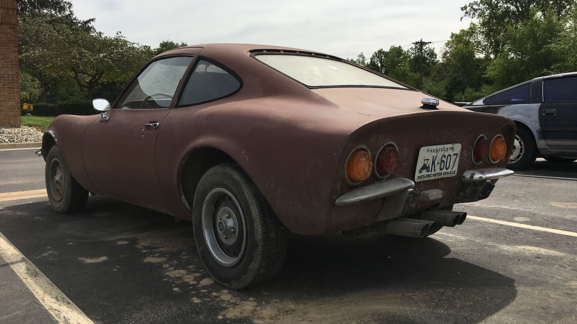 A rusty Opel GT sitting in a parking lot.