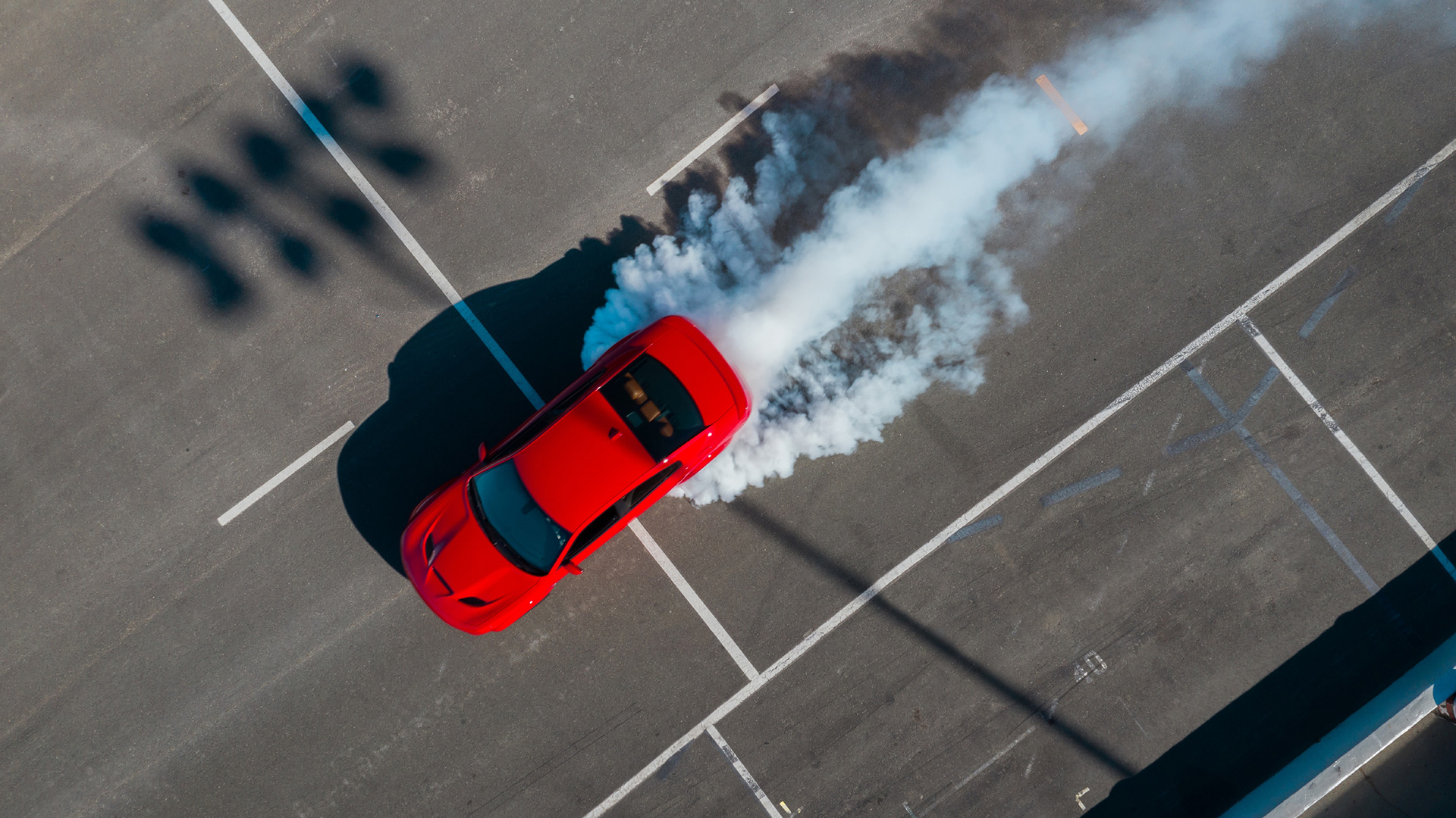 A Dodge Charger SRT Hellcat leaves billows of smoke in a parking lot after a burnout.