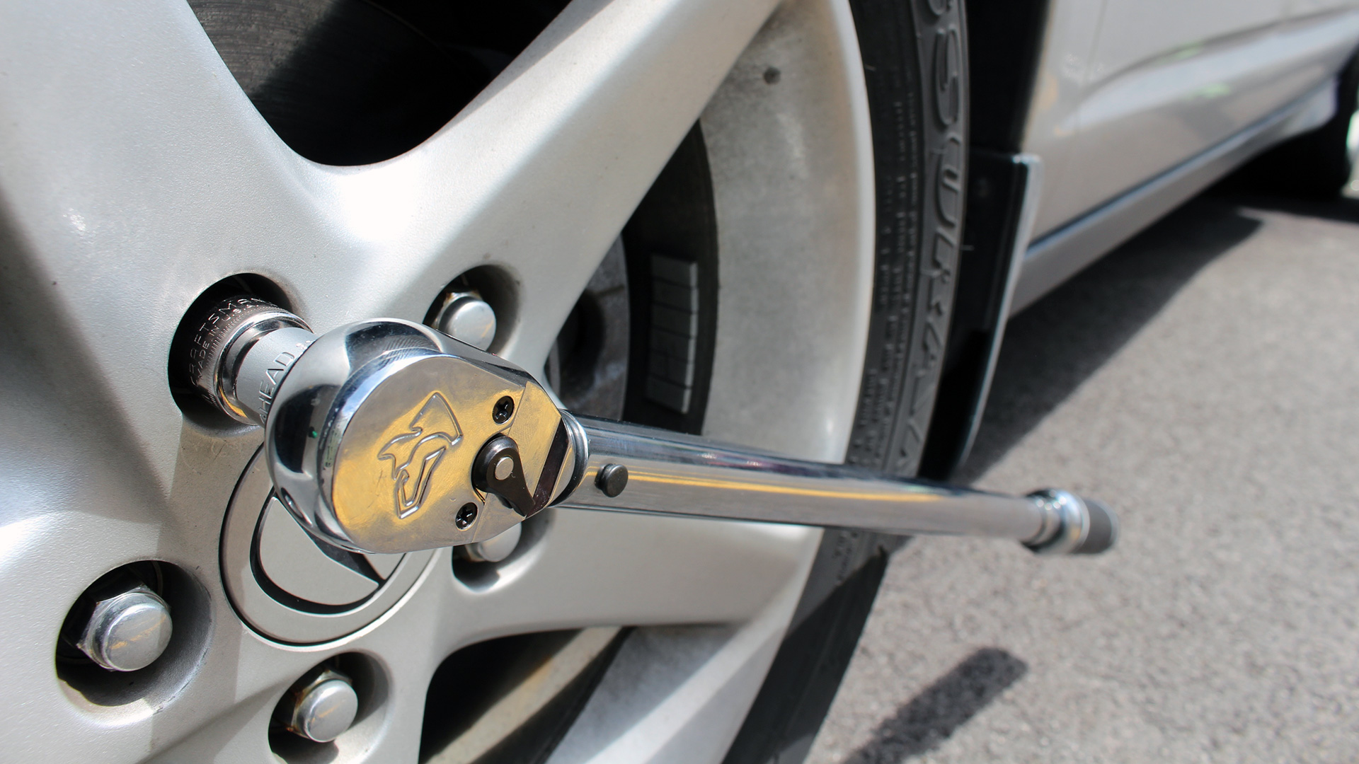 A Husky torque wrench tightening the lug nuts on a 2003 Acura RSX.