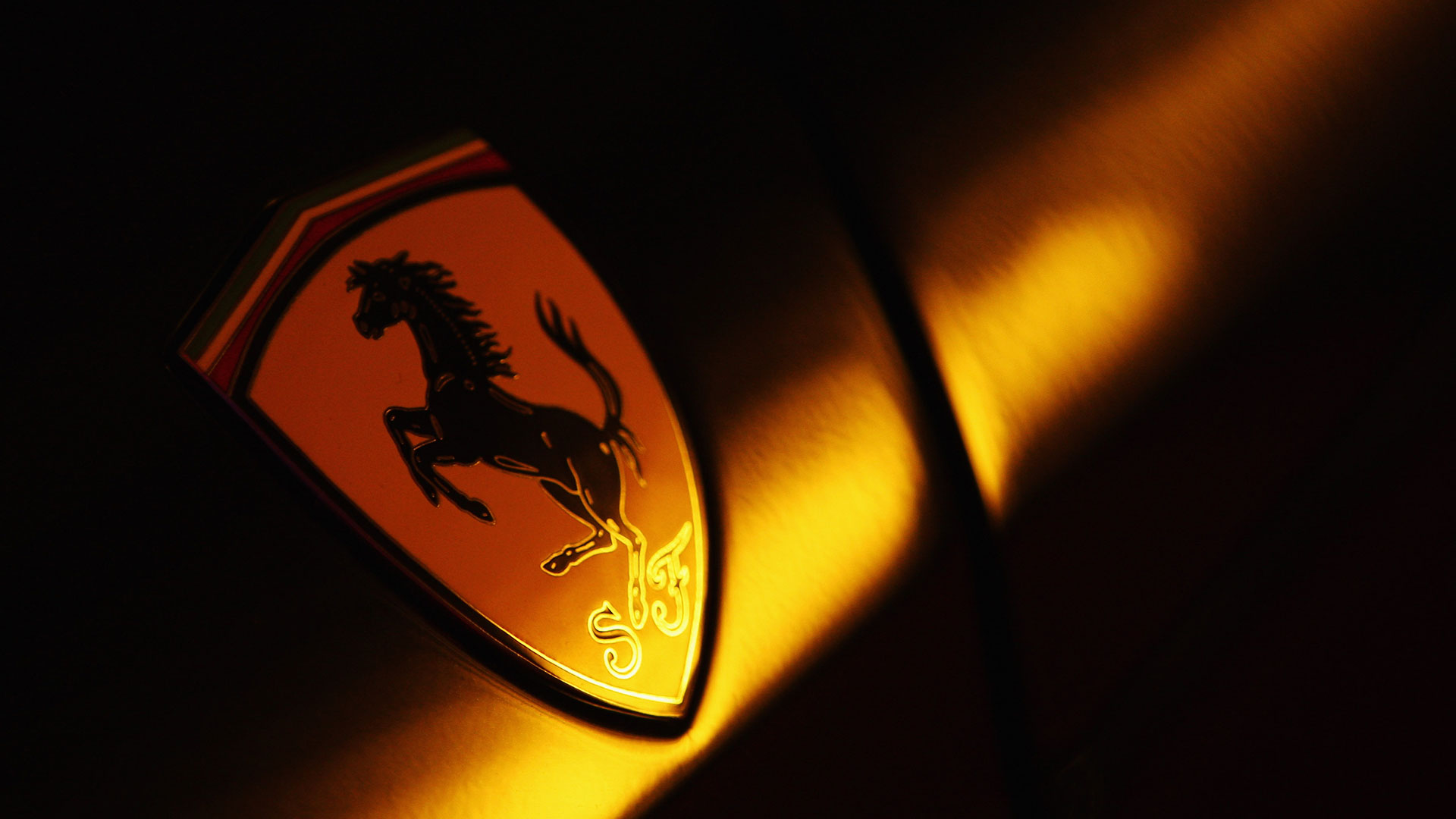 Close-up on a Ferrari badge in dim light.